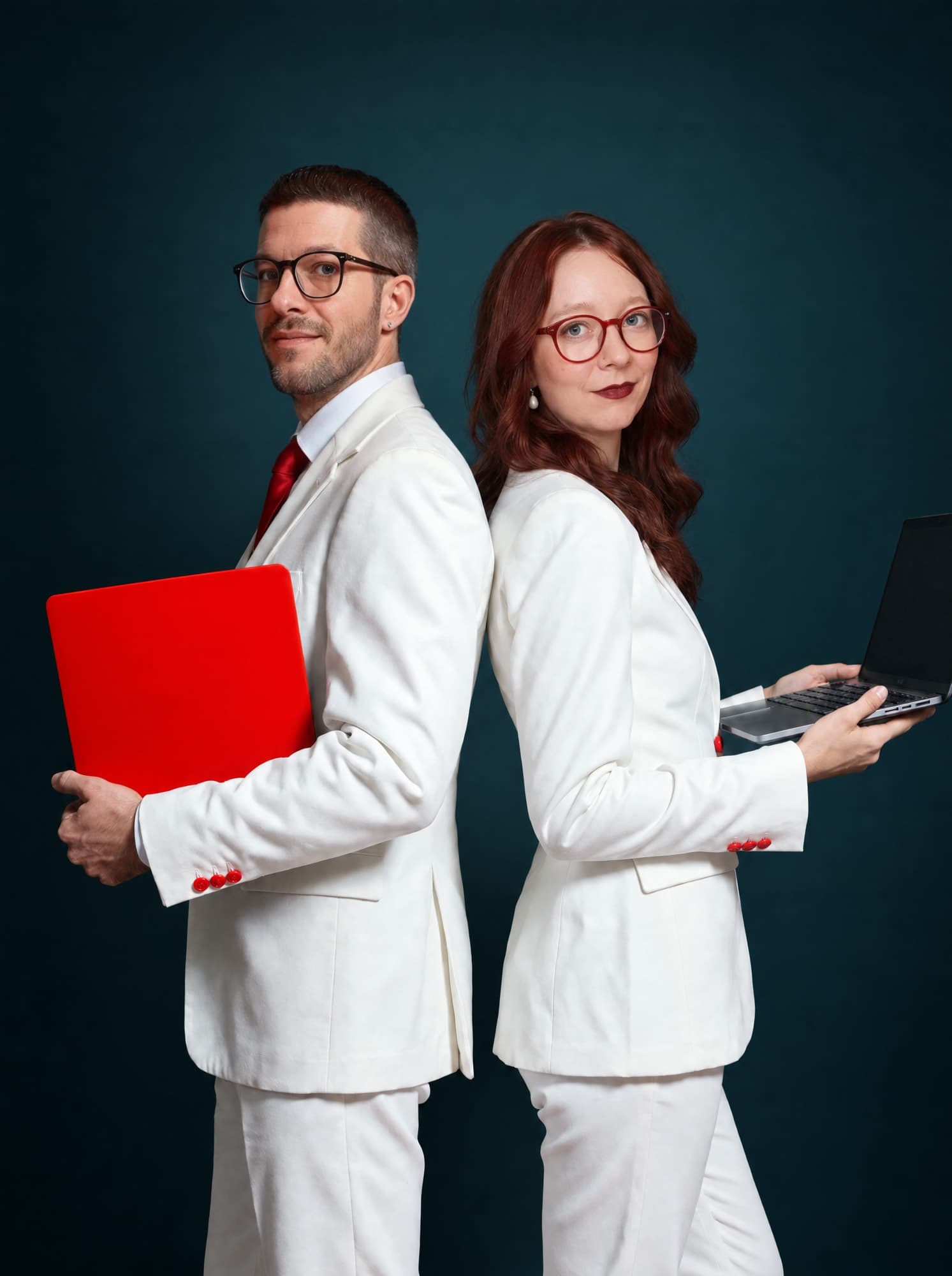 Nils und Jessica Paffen in weißen Anzügen Rücken an Rücken, er mit rotem, sie mit aufgeklapptem Laptop
